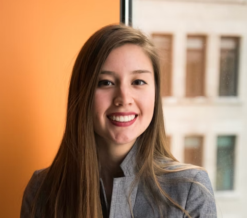 Smiling woman in gray jacket by window