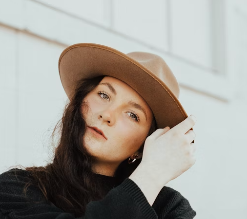 Woman in hat touching her neck outdoors