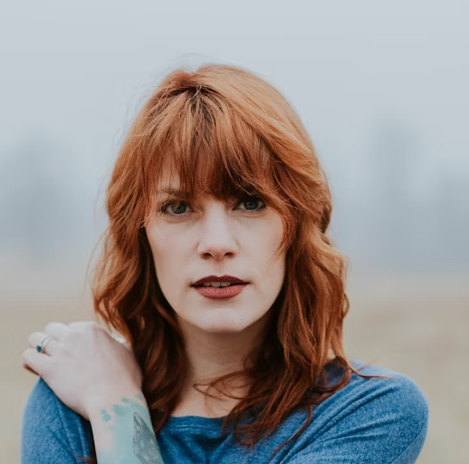 Red-haired woman looking at camera outside